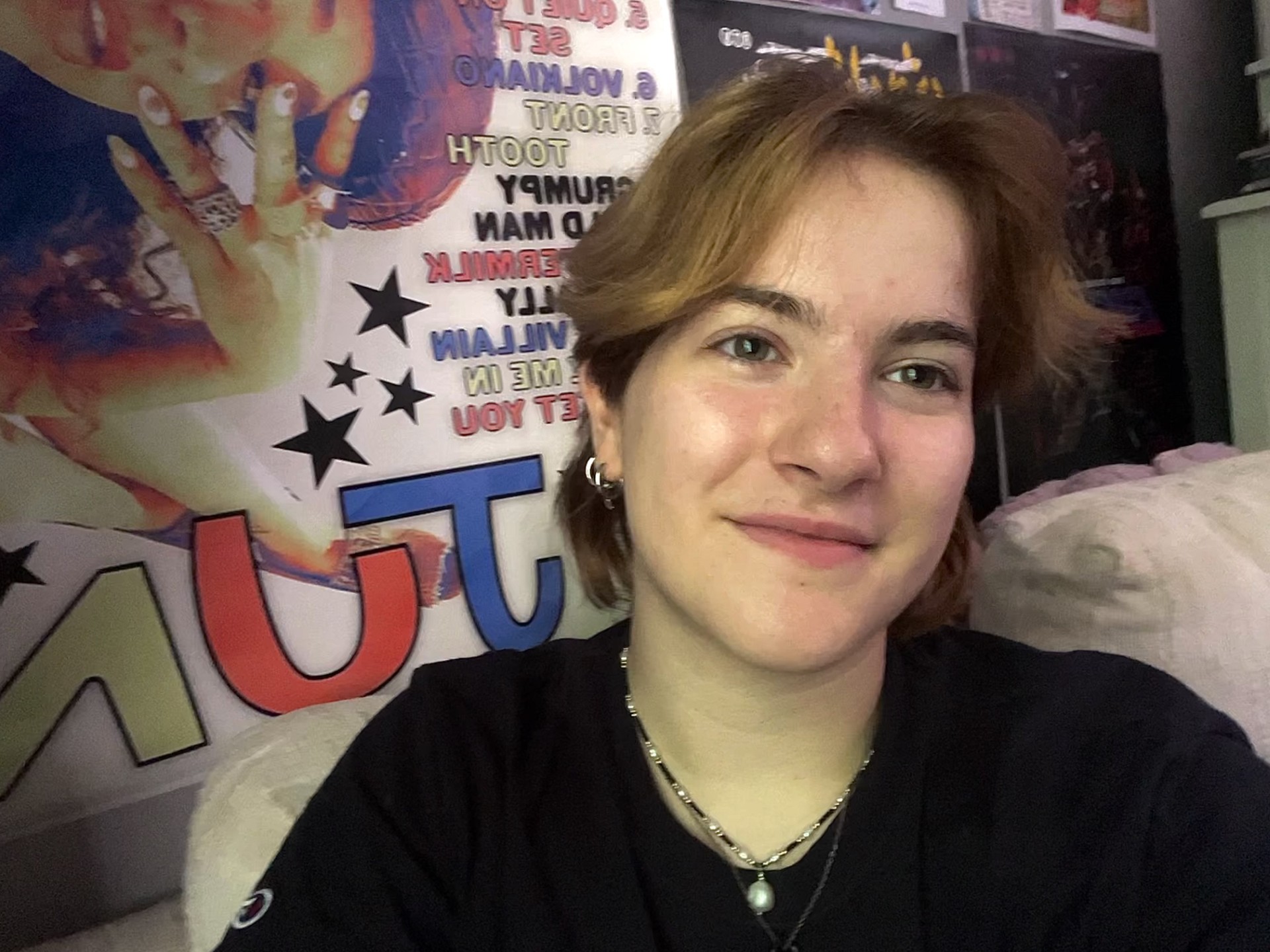 A smiling student in front of wall coverings.